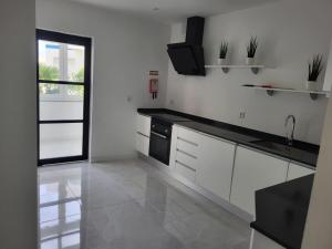 a kitchen with white cabinets and a black counter top at HostelCCPortimão in Portimão