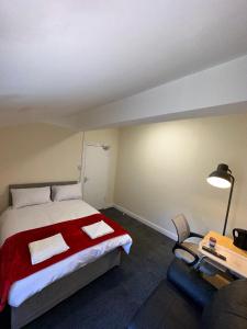 um quarto com uma cama, um candeeiro e uma cadeira em Macclesfield Lodge em Macclesfield