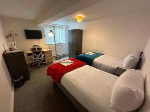 a hotel room with two beds and a desk at Macclesfield Lodge in Macclesfield