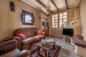 a living room with a leather couch and a tv at Maison pour 8 - proche plages in Mindin