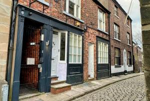 a brick building with black doors on a street at Macclesfield Lodge in Macclesfield