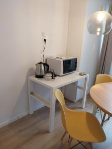 a white desk with a microwave and a chair at Squash Apartments & Studios in Siófok