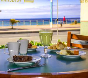 Hotel Verdemar في سلفادور: طاولة مع أطباق من الطعام ومشروب على الشاطئ