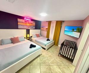a bedroom with two beds and a crib in it at Escape GameRoom, BAR, BBQ, Spacious,KING Bed, All Luxury mattresses, Near Beach, 6 blocks away from Bars, Nite Clubs, Res, Shops in Miami
