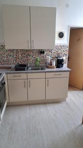 a kitchen with white cabinets and a sink at Schöne Wohnung in Worms Private Gastgeber in Worms +1 photo