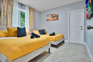 two beds in a room with yellow sheets at Escape GameRoom, BAR, BBQ, Spacious,KING Bed, All Luxury mattresses, Near Beach, 6 blocks away from Bars, Nite Clubs, Res, Shops in Miami