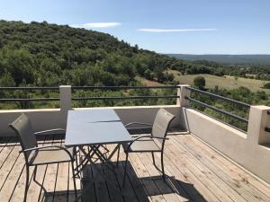 een tafel en stoelen op een balkon met uitzicht bij Studio au calme, grande terrasse avec vue vallée in Ginasservis