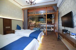 a hotel room with two beds and a flat screen tv at Yi Jiang Lou lnn in Fenghuang