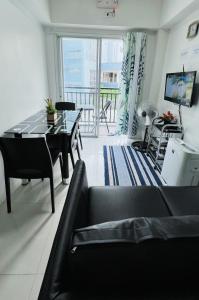 ein Wohnzimmer mit einem schwarzen Sofa und einem Tisch in der Unterkunft Krystal Claine Homestay-BURNHAM HILL in Baguio City