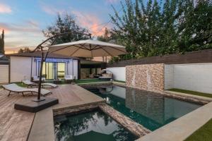 een zwembad met een parasol naast een huis bij ৎ୭ Luxury Reseda with Pool ৎ୭ in Los Angeles