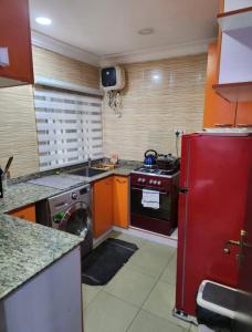 a kitchen with a stove and a red refrigerator at Kings Lux Home in Lagos
