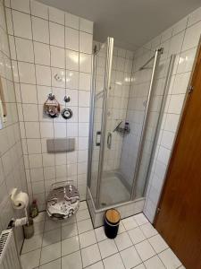 a white tiled bathroom with a shower and a toilet at La Luna in Beuren