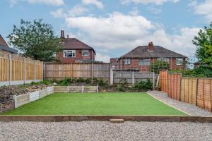 a garden with a artificial lawn in front of a fence at Immaculate 5-Bed House in Leeds in Leeds