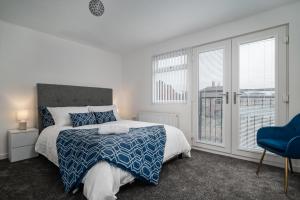 a bedroom with a bed and a blue chair at Immaculate 5-Bed House in Leeds in Leeds