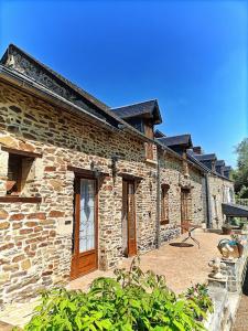 een stenen gebouw met een patio ervoor bij Le Moulin de Benneville chambres d'hôtes, petit déjeuner compris in Cahagnes