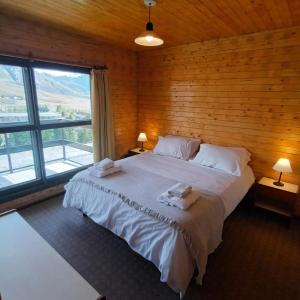 sypialnia z dużym łóżkiem i drewnianą ścianą w obiekcie Apartur Las Leñas w mieście Las Leñas
