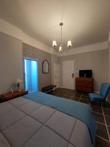 Hotel Lyon by MH في بوينس آيرس: غرفة نوم بسرير كبير وكرسي ازرق