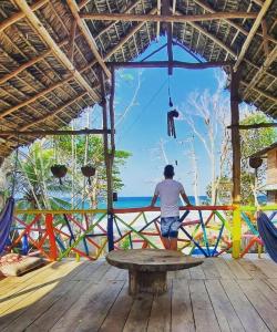 a man standing on a deck looking out at the ocean at Casa hostal playa coral in Capurganá