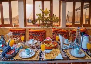 un tavolo pieno di cibo e bevande e un tavolo con cibo di Aladdin Desert Camp a El Gouera