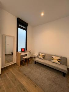 a living room with a couch and a desk with a laptop at Precioso estudio en les Corts Valencianes in Valencia