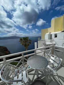 a table and chair on a balcony with a view of the water at VITAMIN STUDIO in Oia +3 photos
