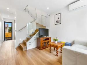 a living room with a couch and a tv and stairs at Wonderful Three Bedroom with Garage in Auckland