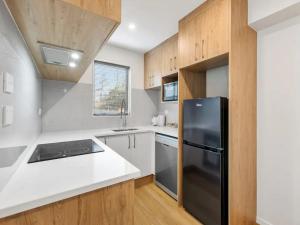 a kitchen with a black refrigerator and wooden cabinets at Wonderful Three Bedroom with Garage in Auckland