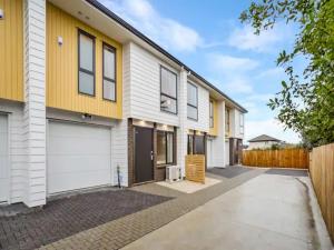 a row of houses with white and yellow at Wonderful Three Bedroom with Garage in Auckland