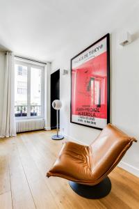 een woonkamer met een filmposter en een leren stoel bij Open-plan apartment in the heart of downtown in Neuilly-sur-Seine
