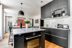 een keuken met zwarte kasten en een aanrecht bij Open-plan apartment in the heart of downtown in Neuilly-sur-Seine