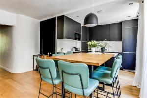 een eetkamer met een houten tafel en blauwe stoelen bij Open-plan apartment in the heart of downtown in Neuilly-sur-Seine