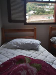 1 dormitorio con cama con almohada y ventana en Casa perto de tudo, pra você ter ótima experiência. Bora Conhecer Ouro Preto...., en Ouro Preto