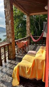 a bed on a porch with a table and chairs at Mansão Espetacular Angra in Angra dos Reis
