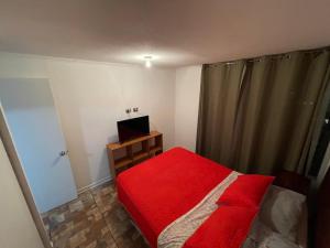a small bedroom with a red bed and a television at VISTA LA CIUDAD Y MAR PISO ALTO 1D in Antofagasta
