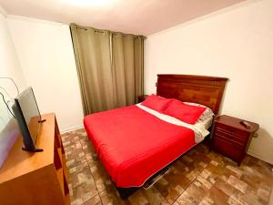 a bedroom with a red bed and a desk at VISTA LA CIUDAD Y MAR PISO ALTO 1D in Antofagasta