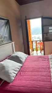 a bedroom with a large bed with a pink blanket at Mansão Espetacular Angra in Angra dos Reis