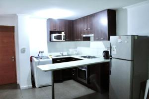 a kitchen with wooden cabinets and a white refrigerator at VISTA LA CIUDAD Y MAR PISO ALTO 1D in Antofagasta
