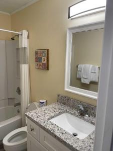 La salle de bains est pourvue d'un lavabo, de toilettes et d'un miroir. dans l'établissement Lighthouse Point Rental 2C, à Tybee Island