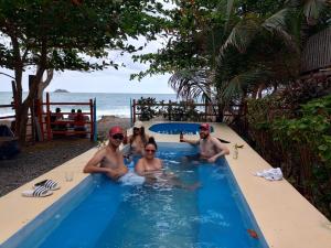 a group of people sitting in a swimming pool at Casa hostal playa coral in Capurganá +24 photos