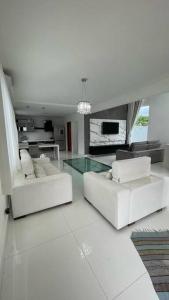 uma sala de estar com dois sofás brancos e uma mesa de vidro em Deliciosa CASA em Caraguatatuba em Caraguatatuba