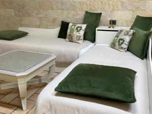 two beds with green and white pillows and a table at Villa Letizia in Anzio