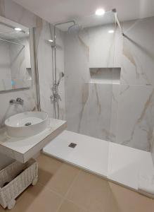 La salle de bains blanche est pourvue d'un lavabo et d'une douche. dans l'établissement Herdade dos Salgados - 5b2a, à Galé