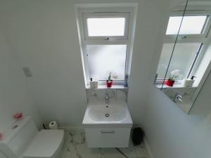 baño blanco con lavabo y ventana en Bright Studio in Wembley 30min to Central London, en Londres
