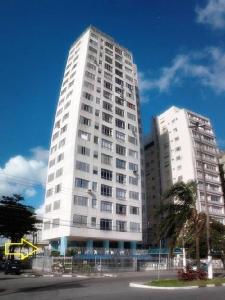 un edificio blanco alto con una palmera delante de él en Apartamento com vista panorâmica, en São Vicente