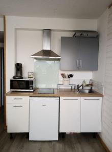 a kitchen with white cabinets and a sink at Appartement avec belle vue sur montagne in Égat