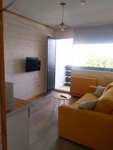 a living room with a yellow couch and a tv at Appartement avec belle vue sur montagne in Égat