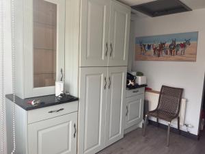 a kitchen with white cabinets and a chair at Old Stagecoach stables rooms only in Crewkerne