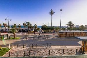 a parking lot with benches and palm trees and the ocean at Dassine View - Luxe - Agadir - 5 Px in Agadir