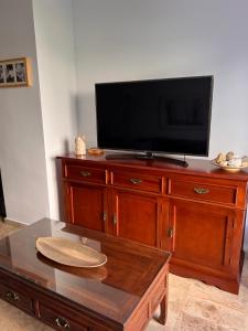 uma televisão em cima de uma cómoda de madeira com uma mesa de centro em Jerez, zona norte, Cadiz, España em Jerez de la Frontera