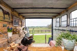 eine offene Tür eines Pferdeanhängers mit Blick auf ein Feld in der Unterkunft Delightful Shepherd hut in Graffham